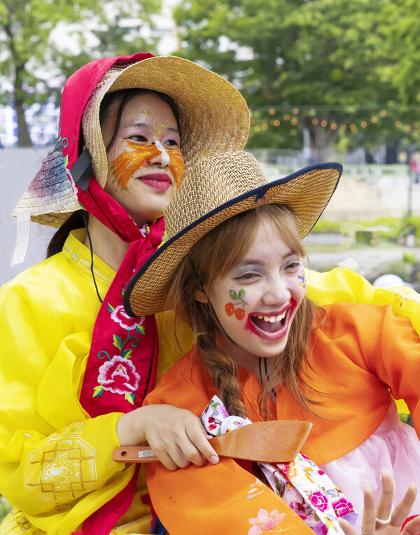 Two laughing pumba performers in face paint and straw hats