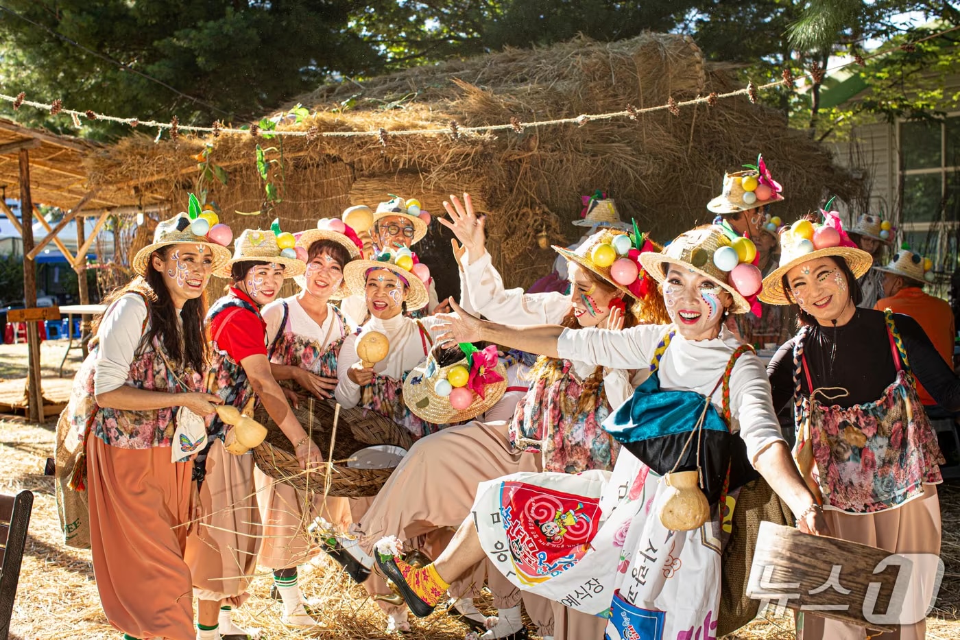 Pumba performers posing by a straw hut in golden light