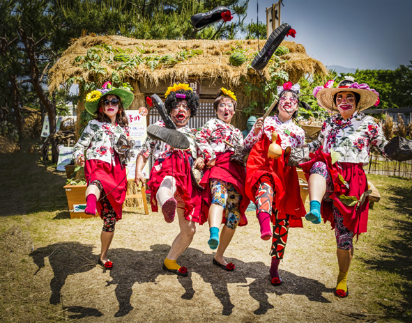 Performers dancing in front of a thatched house