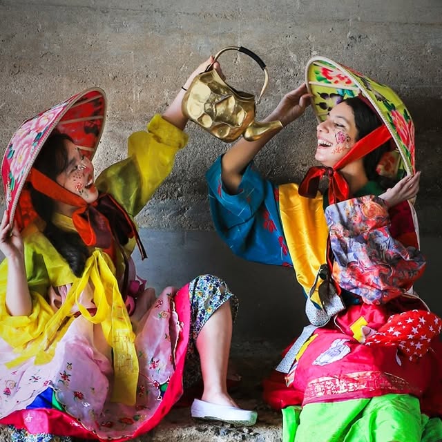 Two pumba performers playing with a brass kettle