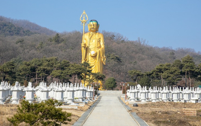 The golden Jijang Bosal statue seen from the stupa-lined approach