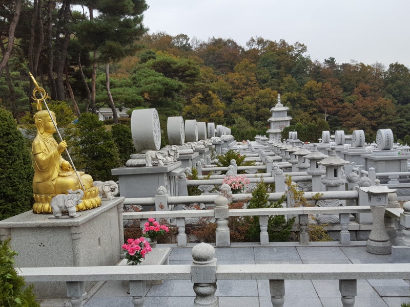 Golden seated statue above the autumn stupa rows
